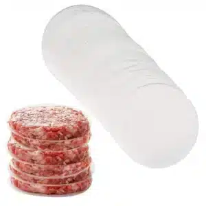 Stack of raw burger patties separated by clear cellophane patty discs, next to a roll of patty discs
