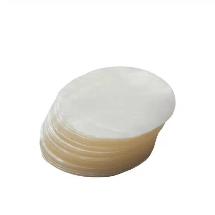 Fanned stack of round cellophane patty discs on a white background